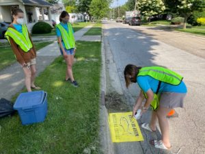 Volunteers spray painting "Drains to Stream Keep it Clean" next to storm drains