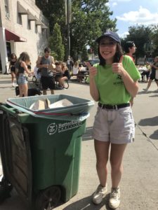 Sweet corn circus volunteer giving a thumbs up next to a composting cart. 