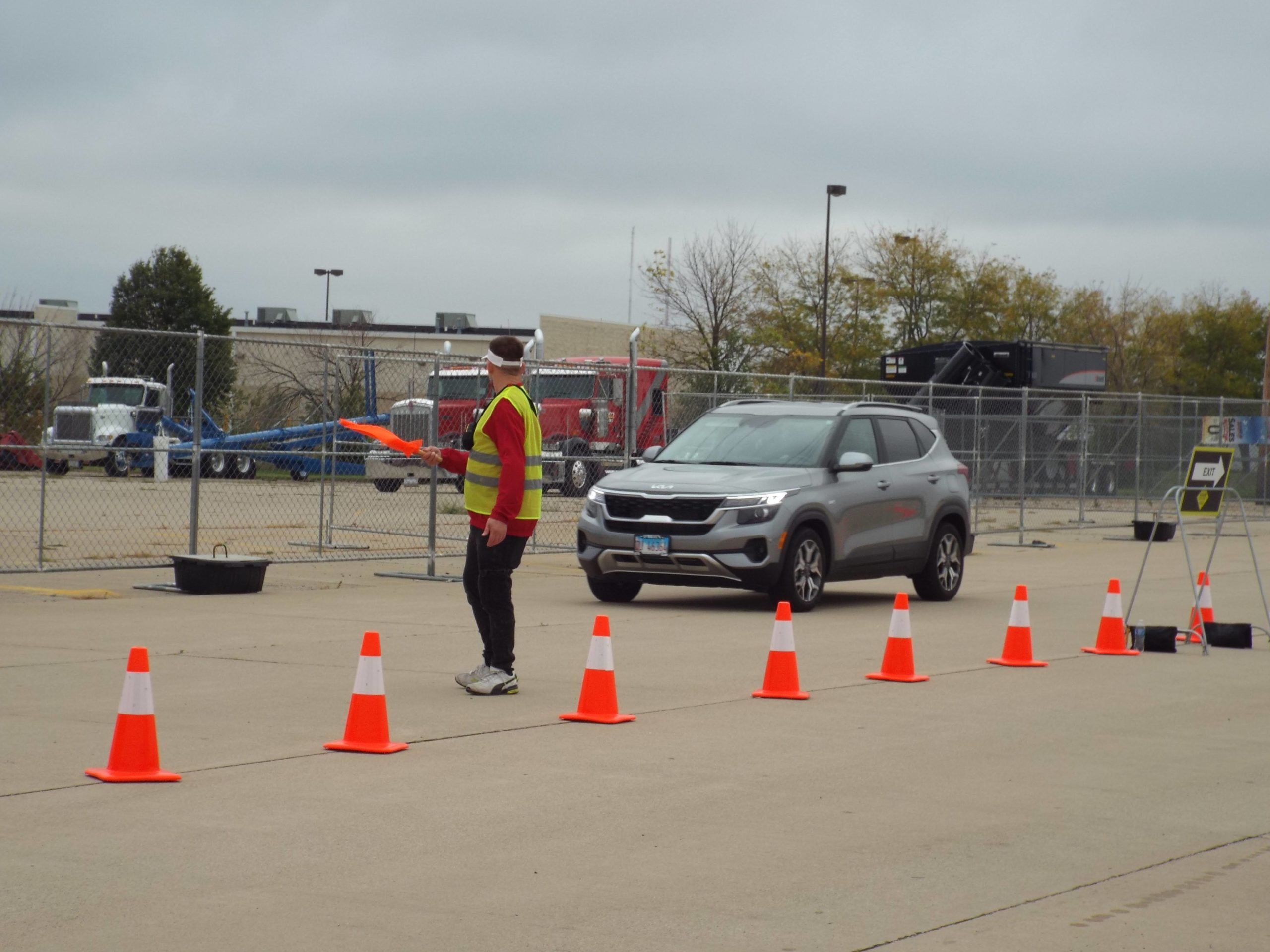 Volunteer in yellow safety vest, helps to direct traffic utilizing a flag