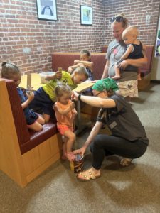 EAC staff member teaching student how to play a stand up base made from a tin can and a string.